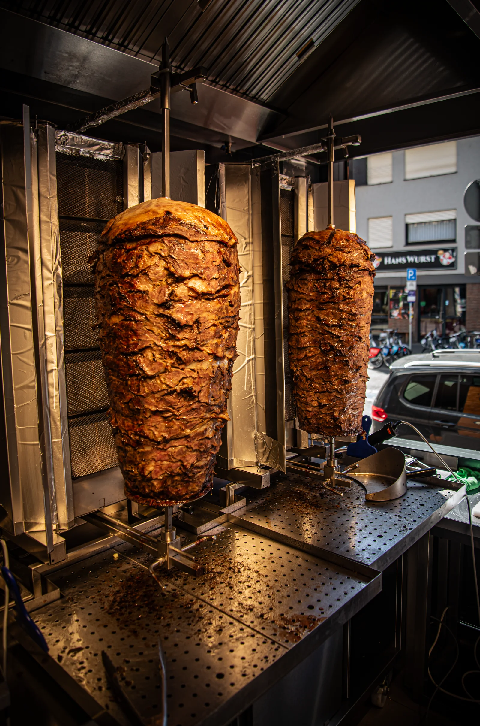 Zwei gegrillte Dönerspieße bei Troja, mit dem vorderen Spieß im Mittelpunkt.
